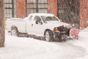 pick-up truck with snowplow attached working the street during a blizzard.